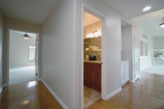 corridor with light wood-style flooring and baseboards
