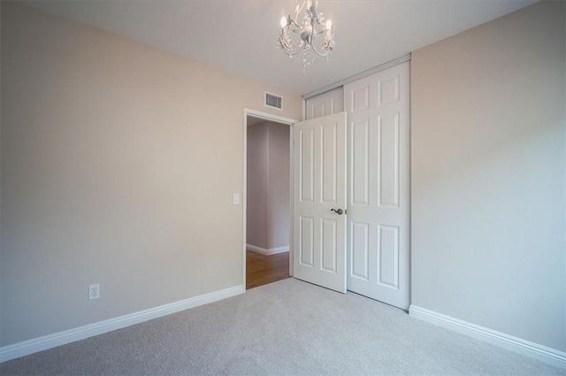 unfurnished bedroom with a chandelier, carpet floors, a closet, and baseboards