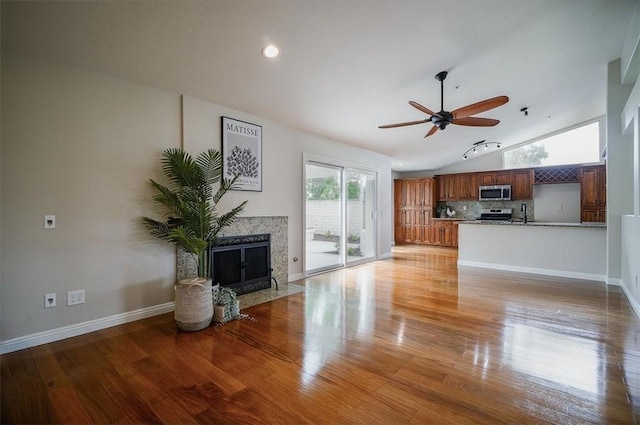 unfurnished living room featuring lofted ceiling, a premium fireplace, a ceiling fan, light wood finished floors, and recessed lighting