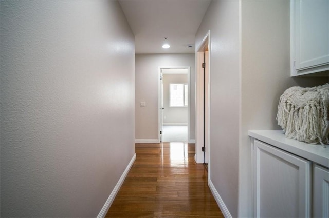 hallway featuring dark wood-style flooring, baseboards, and recessed lighting