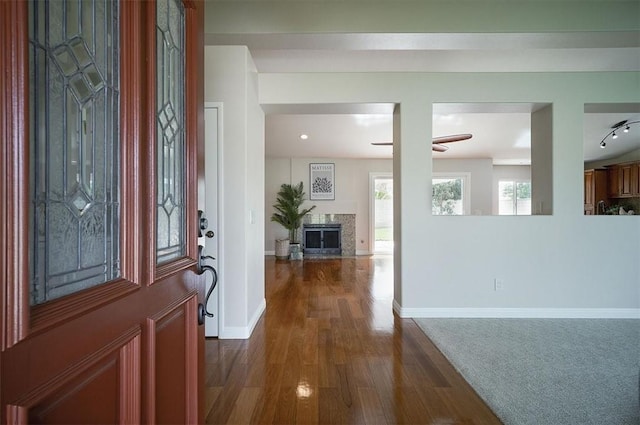 entrance foyer with dark wood-style flooring, a premium fireplace, ceiling fan, and baseboards