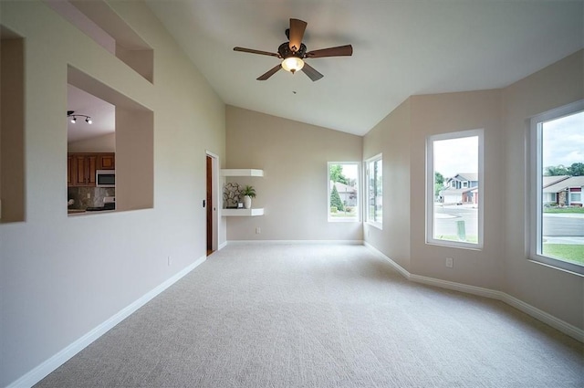 unfurnished room featuring vaulted ceiling, ceiling fan, carpet, and plenty of natural light