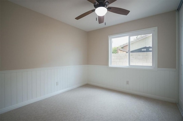 spare room with wainscoting, ceiling fan, and carpet flooring