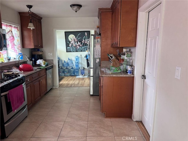 7881 Franklin St, Buena Park, CA 90621 - kitchen featuring appliances with stainless steel finishes, a sink, light tile patterned floors, brown cabinetry, and pendant lighting