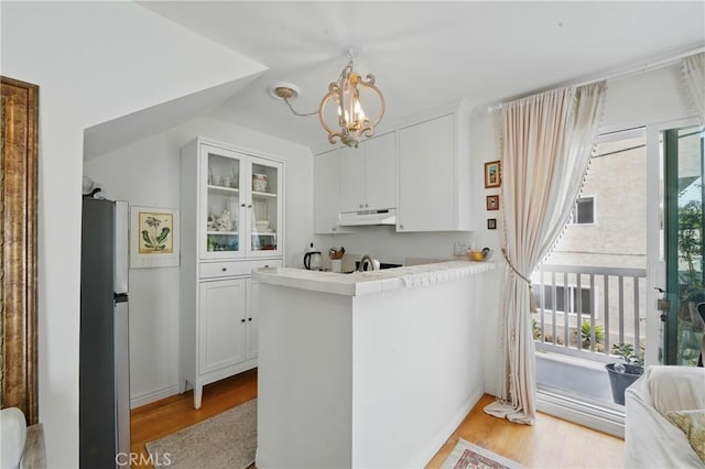 1 Jib St Unit 103, Marina Del Rey, CA 90292 - kitchen featuring under cabinet range hood, freestanding refrigerator, white cabinets, and a chandelier