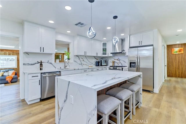 10612 Ketch Ave, Garden Grove, CA 92843 - kitchen featuring appliances with stainless steel finishes, wall chimney exhaust hood, a center island, backsplash, and white cabinets