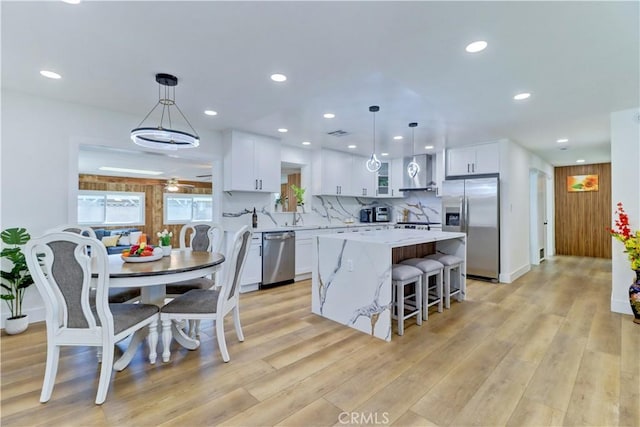 10612 Ketch Ave, Garden Grove, CA 92843 - kitchen featuring stainless steel appliances, a center island, wall chimney exhaust hood, white cabinets, and light countertops