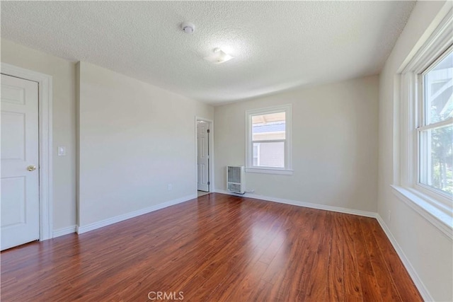 1720 W 25th St, Los Angeles, CA 90018 - unfurnished room with wood finished floors, a textured ceiling, heating unit, baseboards, and a smoke detector