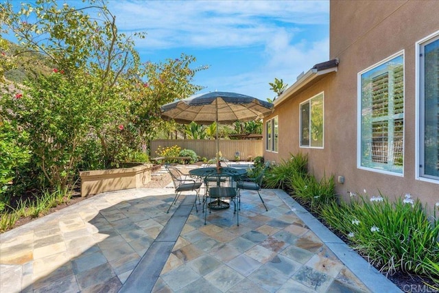 view of patio with outdoor dining space and fence