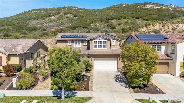 view of front facade with a mountain view, concrete driveway, a garage, stucco siding, and a tiled roof