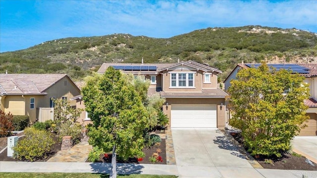 view of front facade featuring a mountain view, concrete driveway, an attached garage, and stucco siding
