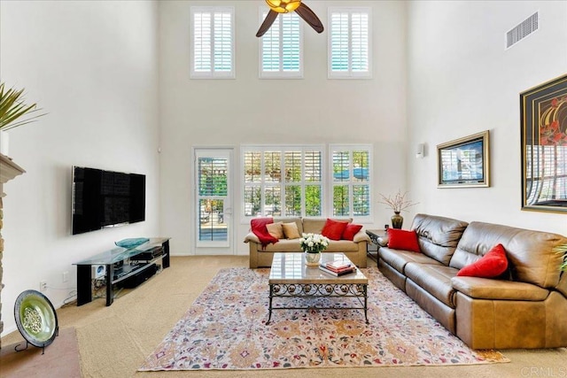 carpeted living area featuring a high ceiling, healthy amount of natural light, and a ceiling fan