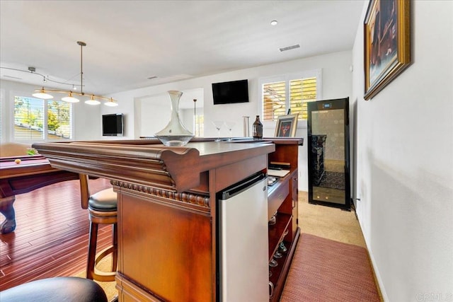 bar area featuring healthy amount of natural light, beverage cooler, pendant lighting, and baseboards