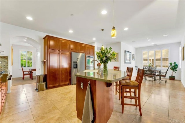 kitchen with high end fridge, a breakfast bar area, light tile patterned floors, hanging light fixtures, and recessed lighting
