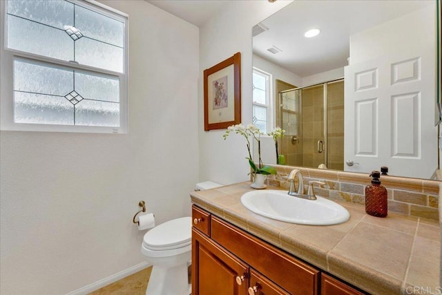 bathroom with a stall shower, toilet, vanity, and baseboards