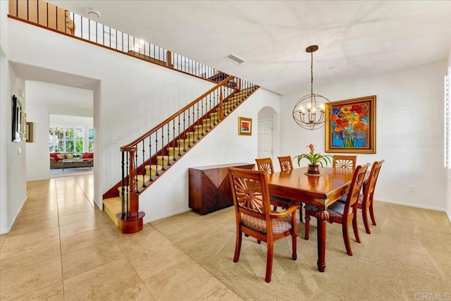 dining room featuring stairway, a chandelier, arched walkways, baseboards, and light tile patterned flooring