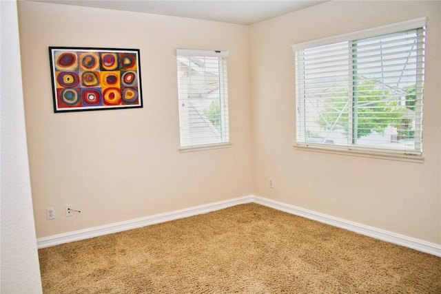carpeted spare room featuring healthy amount of natural light and baseboards