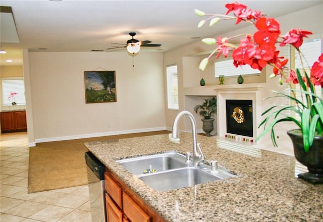 kitchen featuring a sink, dishwasher, brown cabinets, a ceiling fan, and light tile patterned floors