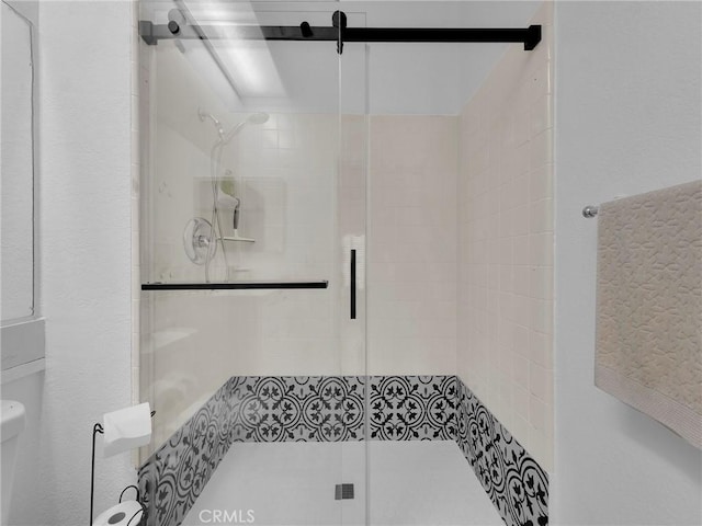 full bath featuring a stall shower and toilet