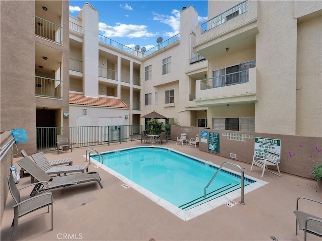 community pool with fence and a patio area