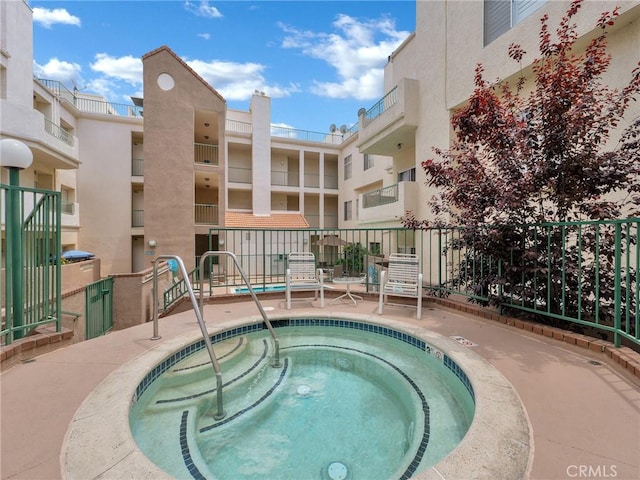 view of swimming pool featuring fence and a community hot tub