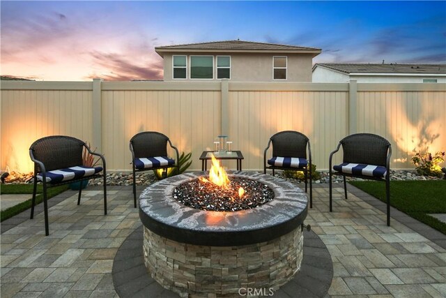 18100 Tableau Way, Saugus, CA 91350 - patio terrace at dusk with an outdoor fire pit, a patio area, and a fenced backyard