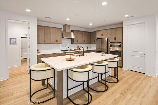18100 Tableau Way, Saugus, CA 91350 - kitchen featuring wall chimney range hood, appliances with stainless steel finishes, a sink, a kitchen breakfast bar, and recessed lighting