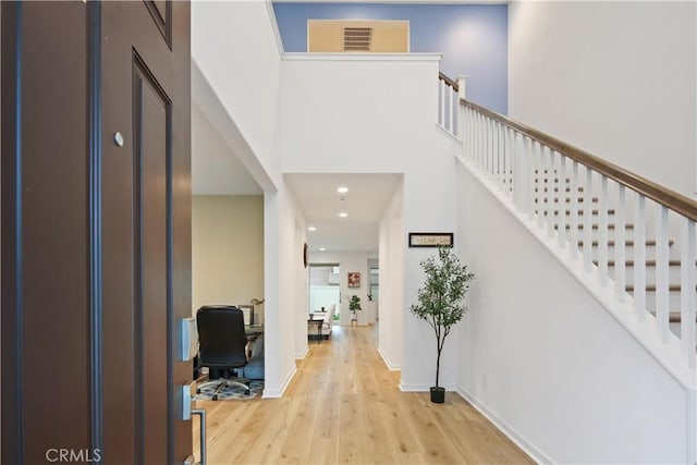 entryway with wood finished floors, recessed lighting, stairway, a high ceiling, and baseboards