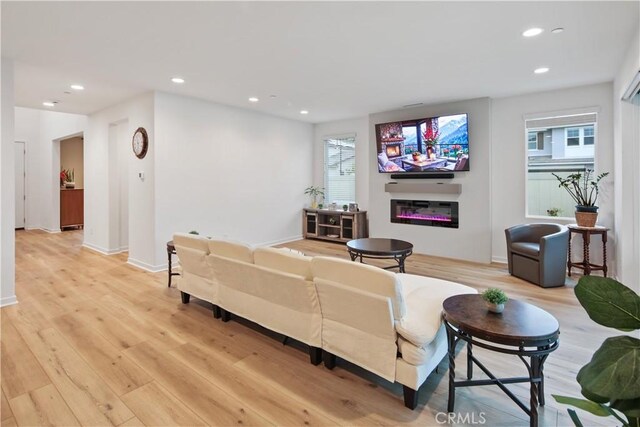 18100 Tableau Way, Saugus, CA 91350 - living area featuring a glass covered fireplace, recessed lighting, light wood-style floors, and healthy amount of natural light