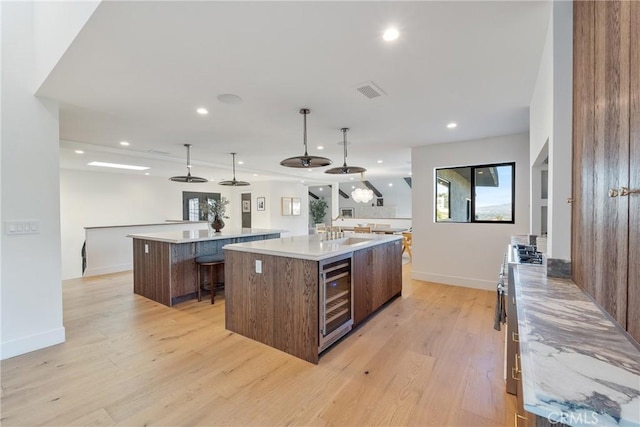 3250 Coldwater Canyon Ave, Studio City, CA 91604 - kitchen with a large island, wine cooler, light wood-style floors, recessed lighting, and light countertops