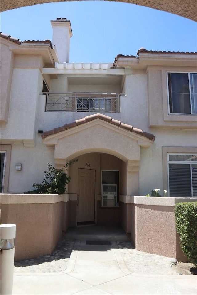 1044 Turner Ave Unit 207, Ontario, CA 91764 - entrance to property with a balcony, stucco siding, a chimney, and a tiled roof