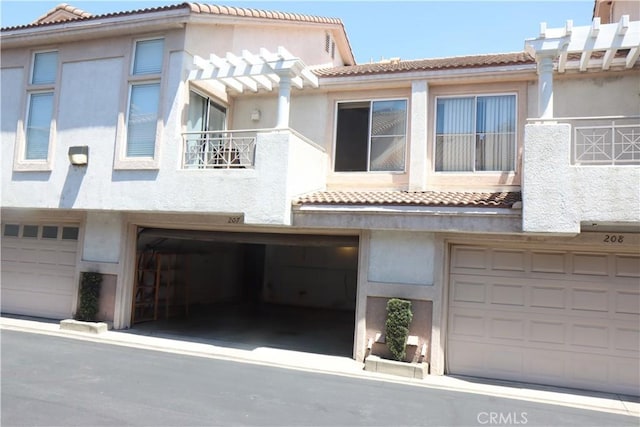 1044 Turner Ave Unit 207, Ontario, CA 91764 - view of front of home with a tiled roof, a balcony, stucco siding, and an attached garage