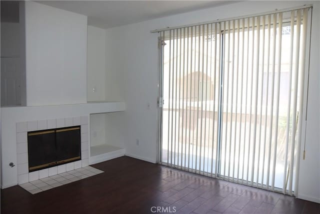 1044 Turner Ave Unit 207, Ontario, CA 91764 - unfurnished living room featuring wood finished floors, a tiled fireplace, and baseboards