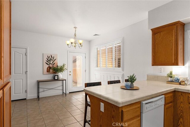 121 Wawona Pl, Chico, CA 95928 - kitchen featuring white dishwasher, a chandelier, a peninsula, light tile patterned floors, and brown cabinets