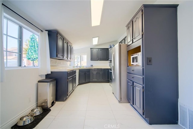 308 13th St, Seal Beach, CA 90740 - kitchen featuring freestanding refrigerator, white microwave, light countertops, gray cabinetry, and vaulted ceiling