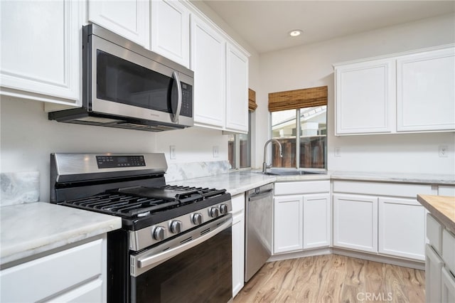 126 Schooner Ct, San Jacinto, CA 92583 - kitchen with appliances with stainless steel finishes, white cabinets, a sink, light wood finished floors, and recessed lighting