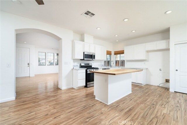 126 Schooner Ct, San Jacinto, CA 92583 - kitchen with stainless steel appliances, wood counters, a kitchen island, arched walkways, and plenty of natural light