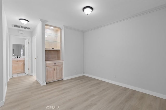 spare room featuring light wood-style flooring, baseboards, and crown molding