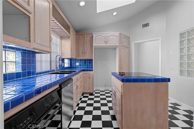 kitchen with light flooring, a skylight, tile counters, vaulted ceiling, and light brown cabinetry