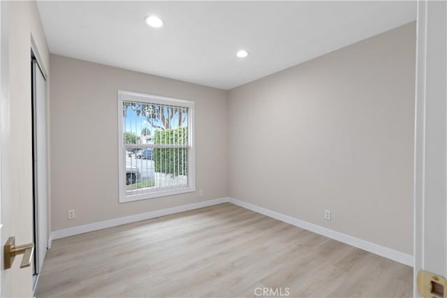 spare room featuring light wood finished floors, baseboards, and recessed lighting
