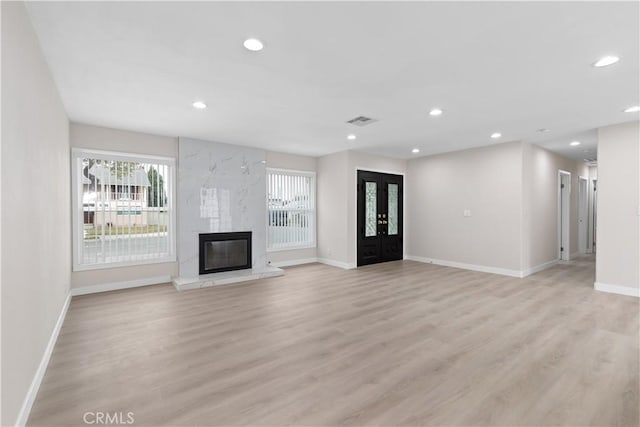 unfurnished living room featuring a fireplace, baseboards, light wood-style flooring, and recessed lighting