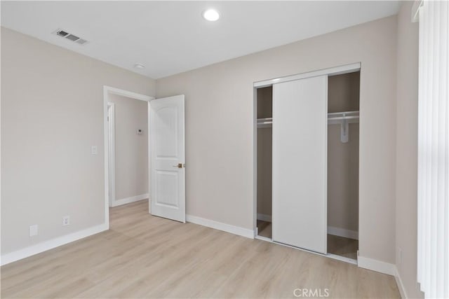 unfurnished bedroom with wood finished floors, a closet, baseboards, and recessed lighting