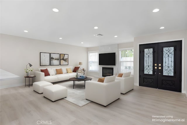 living room with light wood-style flooring, baseboards, recessed lighting, a fireplace, and french doors