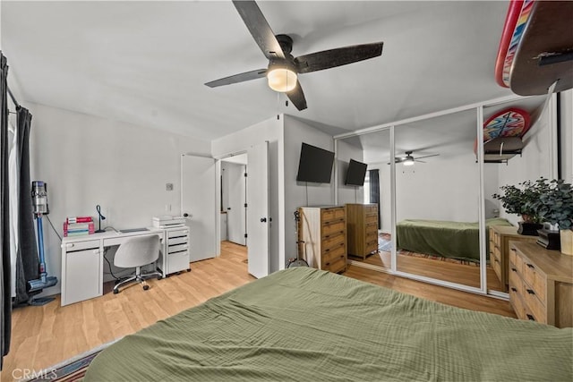 bedroom featuring light wood finished floors, an office area, and a ceiling fan