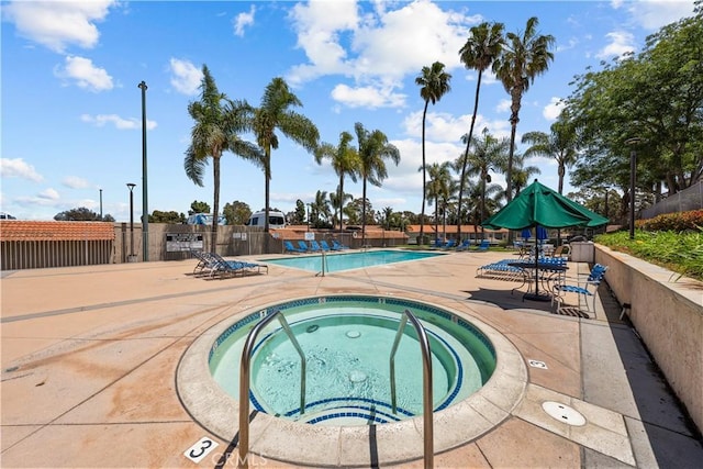 community pool featuring a community hot tub, a patio area, and fence