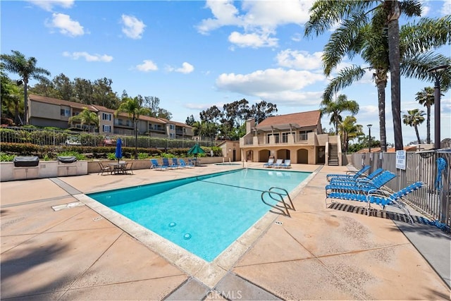 community pool featuring fence, a patio area, and stairway