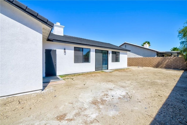 47432 Bahama Ct, Indio, CA 92201 - rear view of property featuring stucco siding, a chimney, and fence