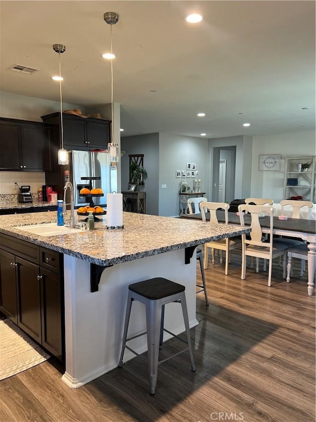 34988 Keiser Ct, Beaumont, CA 92223 - kitchen featuring dark wood-style flooring, a kitchen bar, light stone counters, recessed lighting, and stainless steel refrigerator with ice dispenser