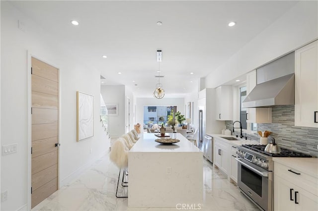 125 8th St, Huntington Beach, CA 92648 - kitchen featuring appliances with stainless steel finishes, wall chimney exhaust hood, a sink, a kitchen island, and light marble finish flooring