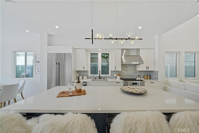 125 8th St, Huntington Beach, CA 92648 - kitchen with wall chimney exhaust hood, high end fridge, a sink, backsplash, and plenty of natural light